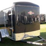 a black trailer parked in a grassy field