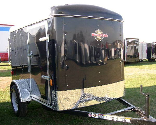 a black trailer parked in a grassy field