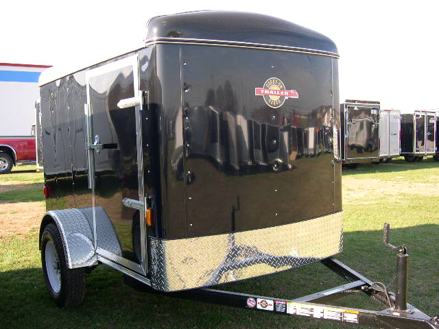 a black trailer parked in a grassy field