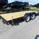 a wooden flatbed trailer is parked on the side of the road .