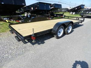 a wooden flatbed trailer is parked on the side of the road .