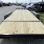a trailer with a wooden deck is parked in a parking lot