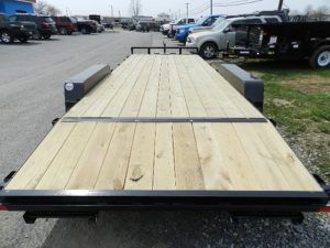 a trailer with a wooden deck is parked in a parking lot