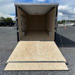 an atc trailer is sitting in a gravel lot with the door open .