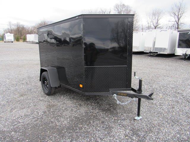 a black trailer is parked in a gravel lot .