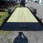 a trailer with a wooden deck is parked on the side of the road .