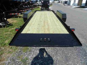 a trailer with a wooden deck is parked on the side of the road .