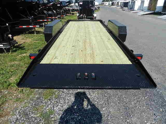 a trailer with a wooden deck is parked on the side of the road .