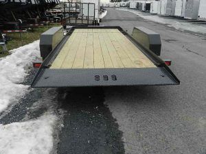 a CAM Superline trailer with a wooden deck parked on the side of the road