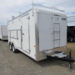 a white trailer with a ladder attached to it is parked in a gravel lot