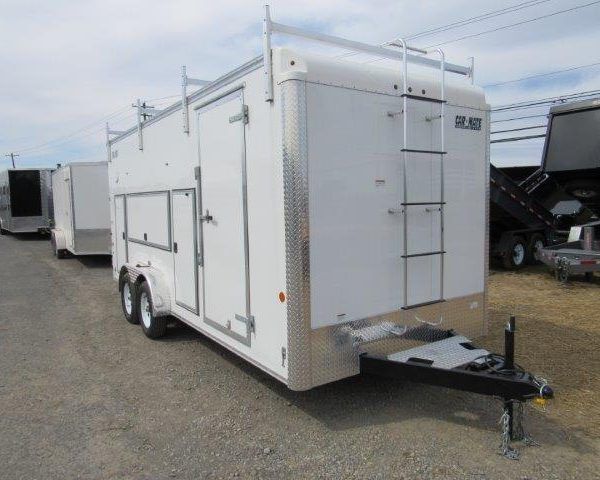 a white trailer with a ladder attached to it is parked in a gravel lot