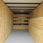 the inside of a trailer with wooden walls and shelves .