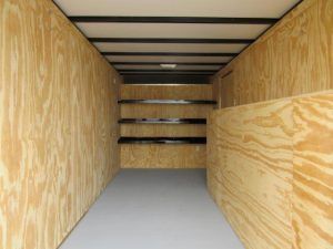 the inside of a trailer with wooden walls and shelves .