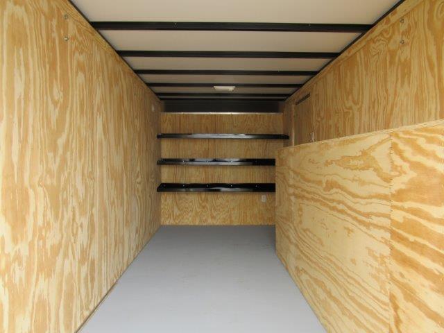 the inside of a trailer with wooden walls and shelves .