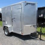 a small aluminum trailer is parked on the side of the road next to a dump trailer