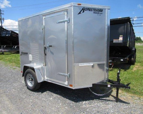 a small aluminum trailer is parked on the side of the road next to a dump trailer