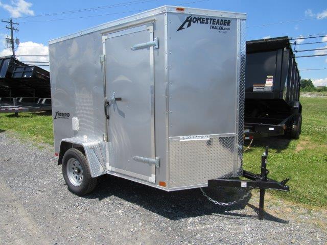 a small aluminum trailer is parked on the side of the road next to a dump trailer