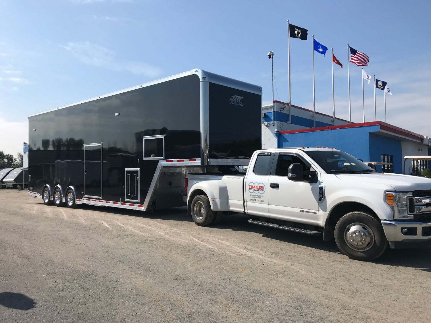 white pick up truck hauling large black enclosed trailer