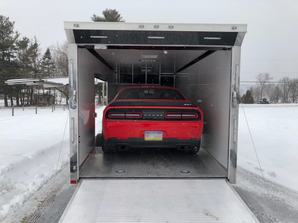 Trailer with a car inside driving in snowy road