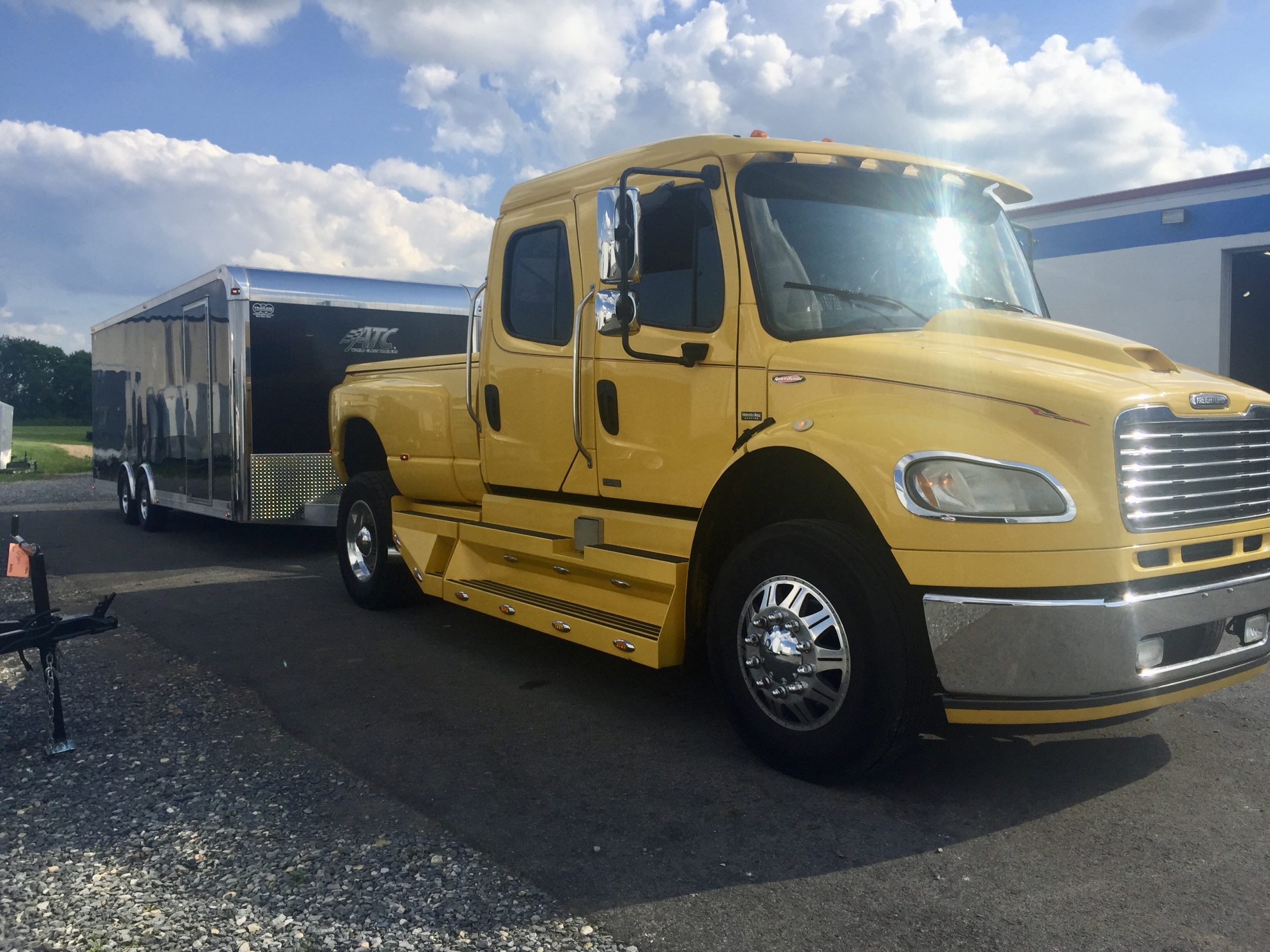 Yellow truck pulling a black enclosed trailer