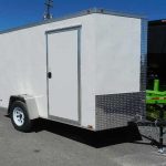 a white trailer is parked on the side of the road .