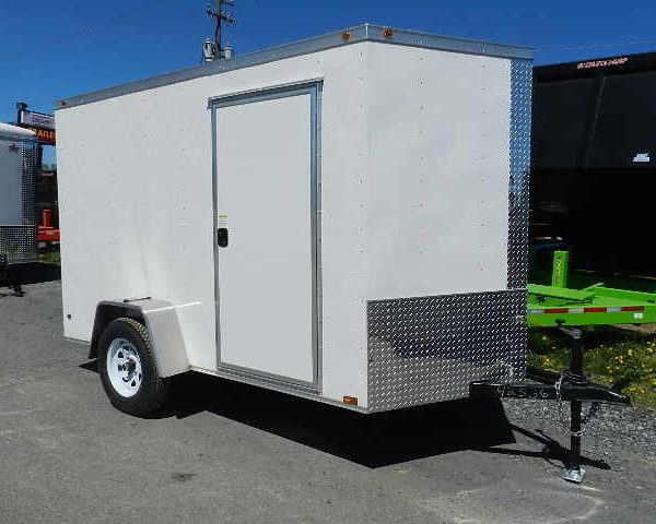 a white trailer is parked on the side of the road .