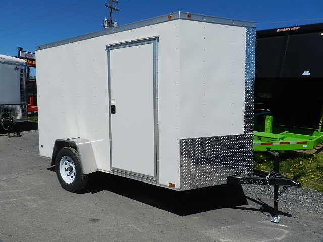 a white trailer is parked on the side of the road .