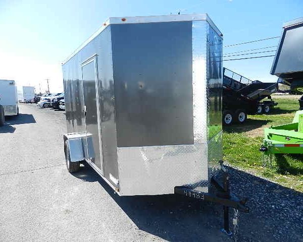 a black and silver trailer is parked on the side of the road in a parking lot .