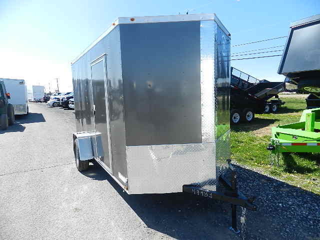 a black and silver trailer is parked on the side of the road in a parking lot .