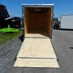 an empty trailer with a wooden ramp is parked on the side of the road .