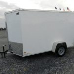 a white trailer is parked on the side of a gravel road .