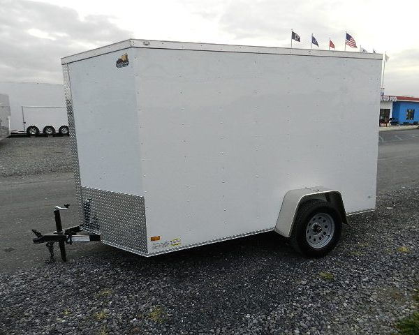 a white trailer is parked on the side of a gravel road .