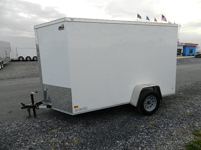 a white trailer is parked on the side of a gravel road .