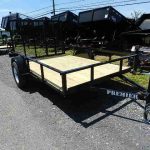 a trailer with a wooden deck is parked on the side of the road .