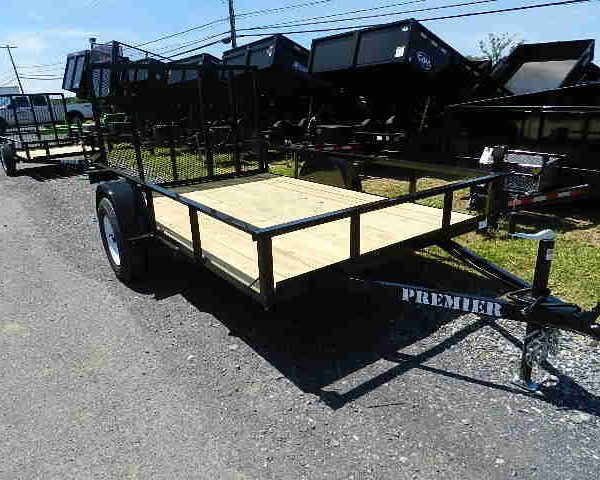 a trailer with a wooden deck is parked on the side of the road .