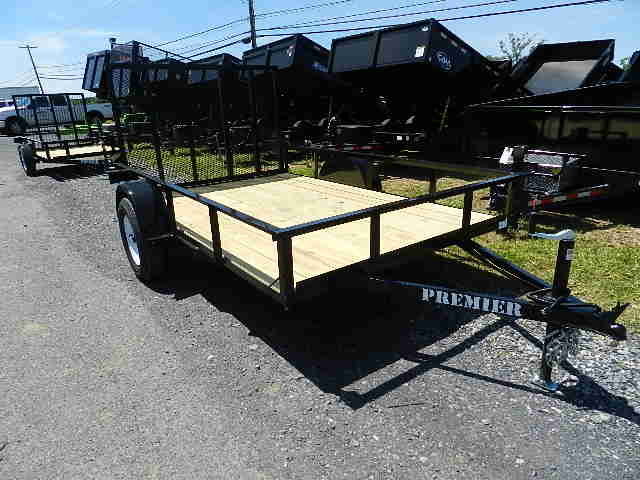 a trailer with a wooden deck is parked on the side of the road .