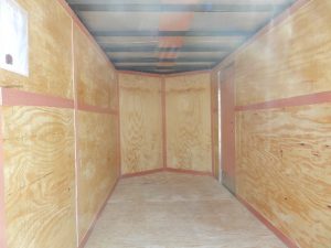 an empty trailer with wooden walls and a metal roof .