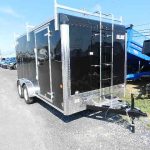a black trailer with a ladder attached to it parked on the side of the road