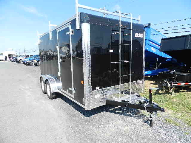 a black trailer with a ladder attached to it parked on the side of the road