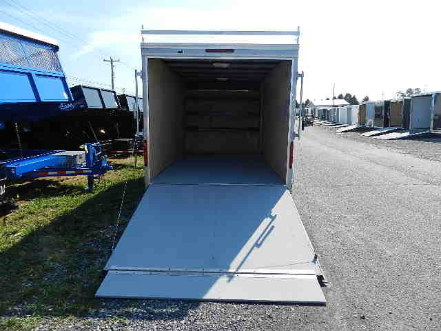 a trailer with the door open is parked on the side of the road .