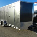 a black and silver trailer is parked in front of a building .