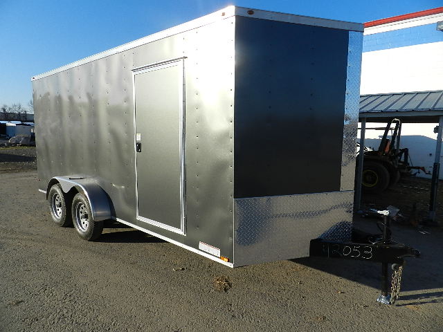 a black and silver trailer is parked in front of a building .