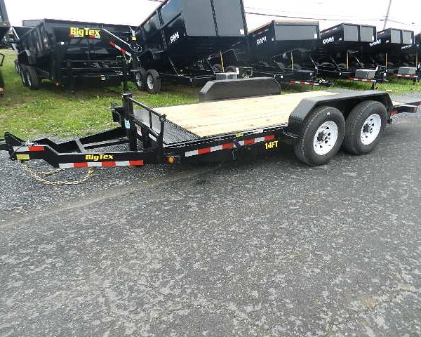 a Big Tex trailer parked on the side of the road next to a row of dump trailers