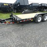 a Big Tex trailer parked on the side of the road next to a row of dump trailers