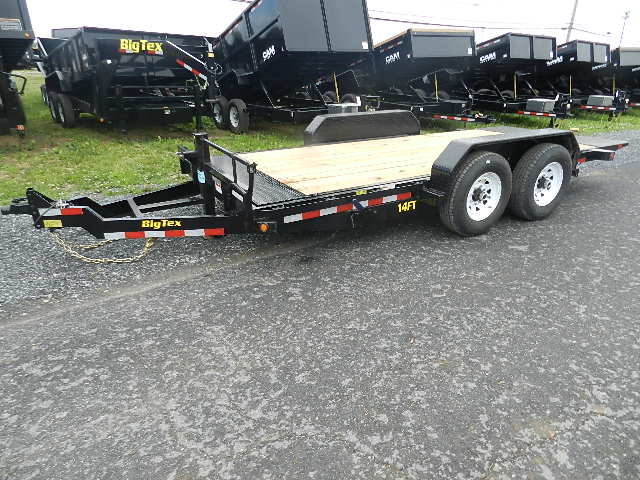 a Big Tex trailer parked on the side of the road next to a row of dump trailers