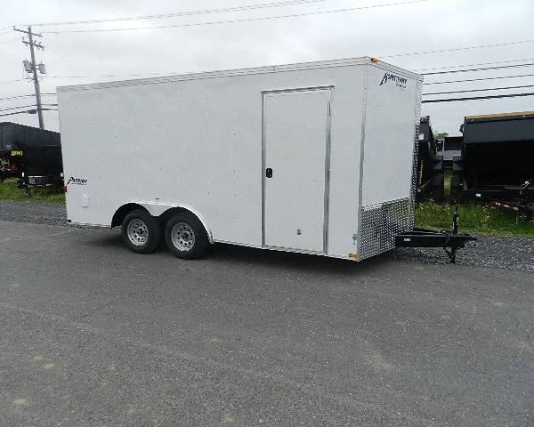 a white trailer is parked on the side of the road .