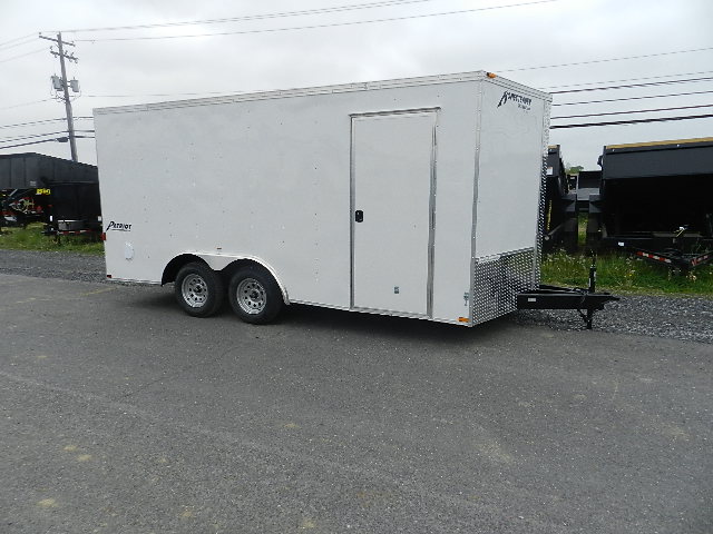 a white trailer is parked on the side of the road .