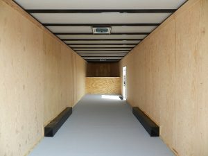a long hallway with wooden walls and a gray floor .
