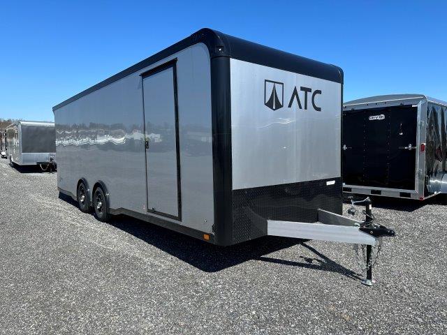 a gray and black trailer is parked in a gravel lot .