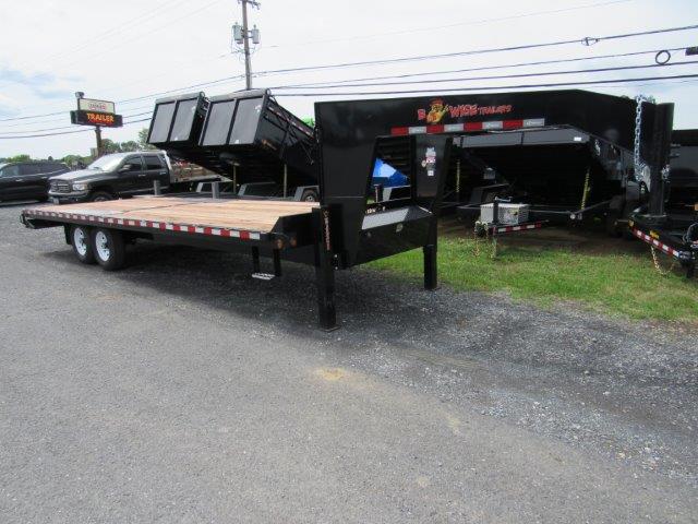 a flatbed trailer is parked on the side of the road next to a dump trailer .
